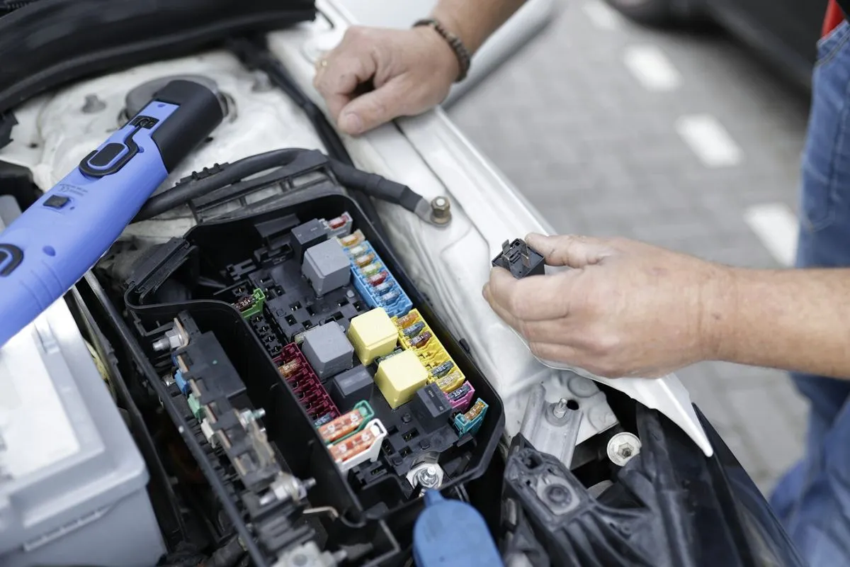 Mechanik pochylony nad otwartą komorą silnika podczas przeglądu auta