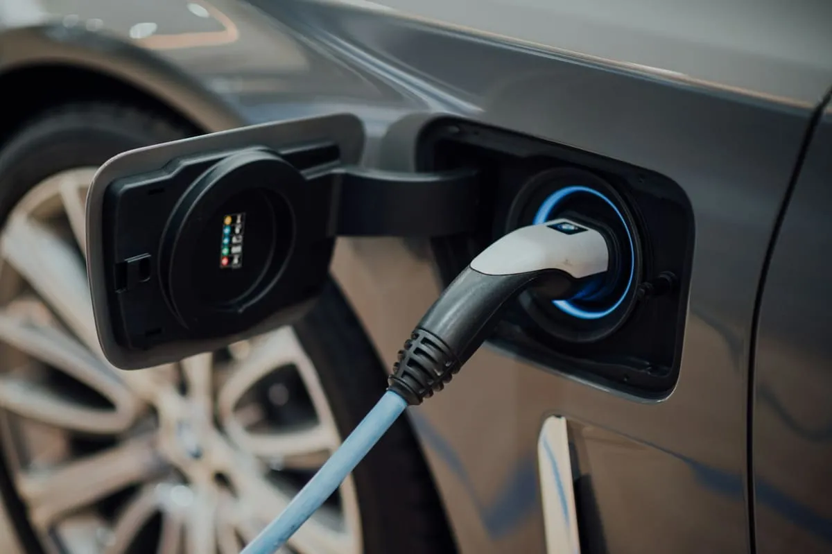 Wtyczka ładowania w gnieździe samochodu elektrycznego z podświetlonym na niebiesko portem