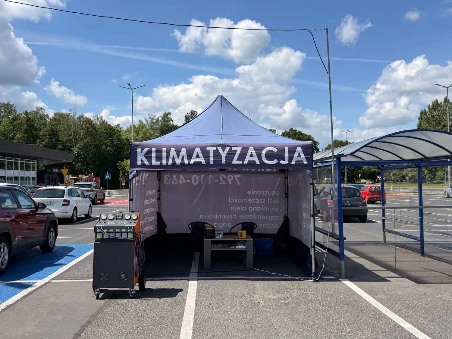 Punkt serwisowy Klima w Aucie na parkingu: namiot z napisem Klimatyzacja i stacja do nabijania klimatyzacji