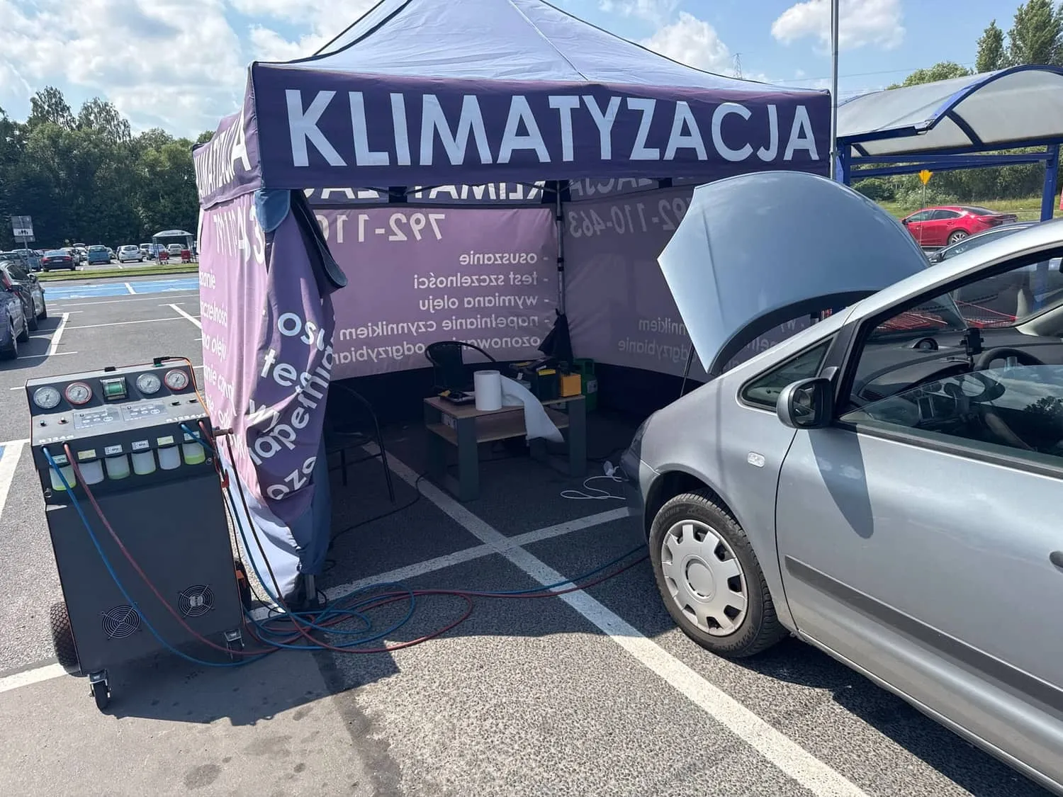 Srebrny hatchback podłączony do stacji klimatyzacji na parkingu Carrefour w Pabianicach