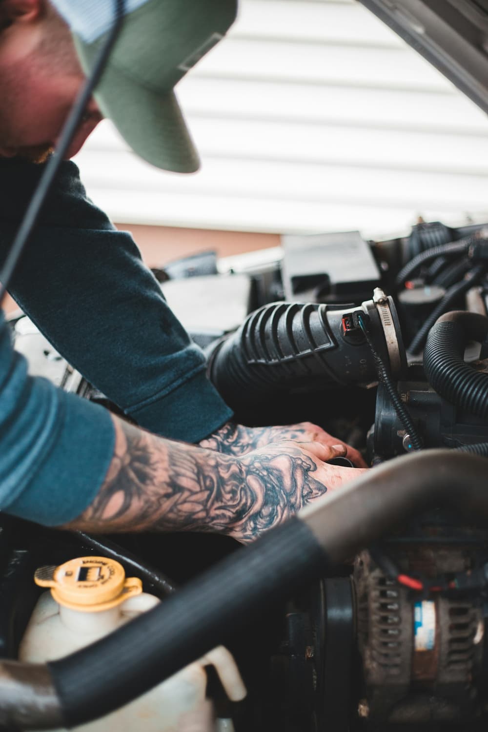 Dłonie mechanika pracujące przy przewodach w komorze silnika