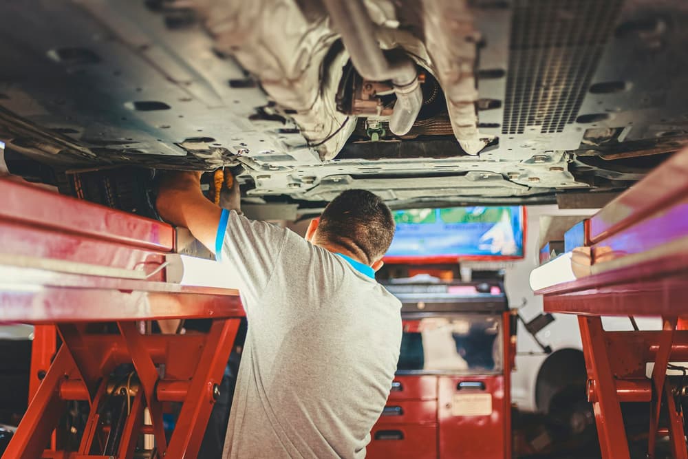 Mechanik pracujący pod autem uniesionym na podnośniku