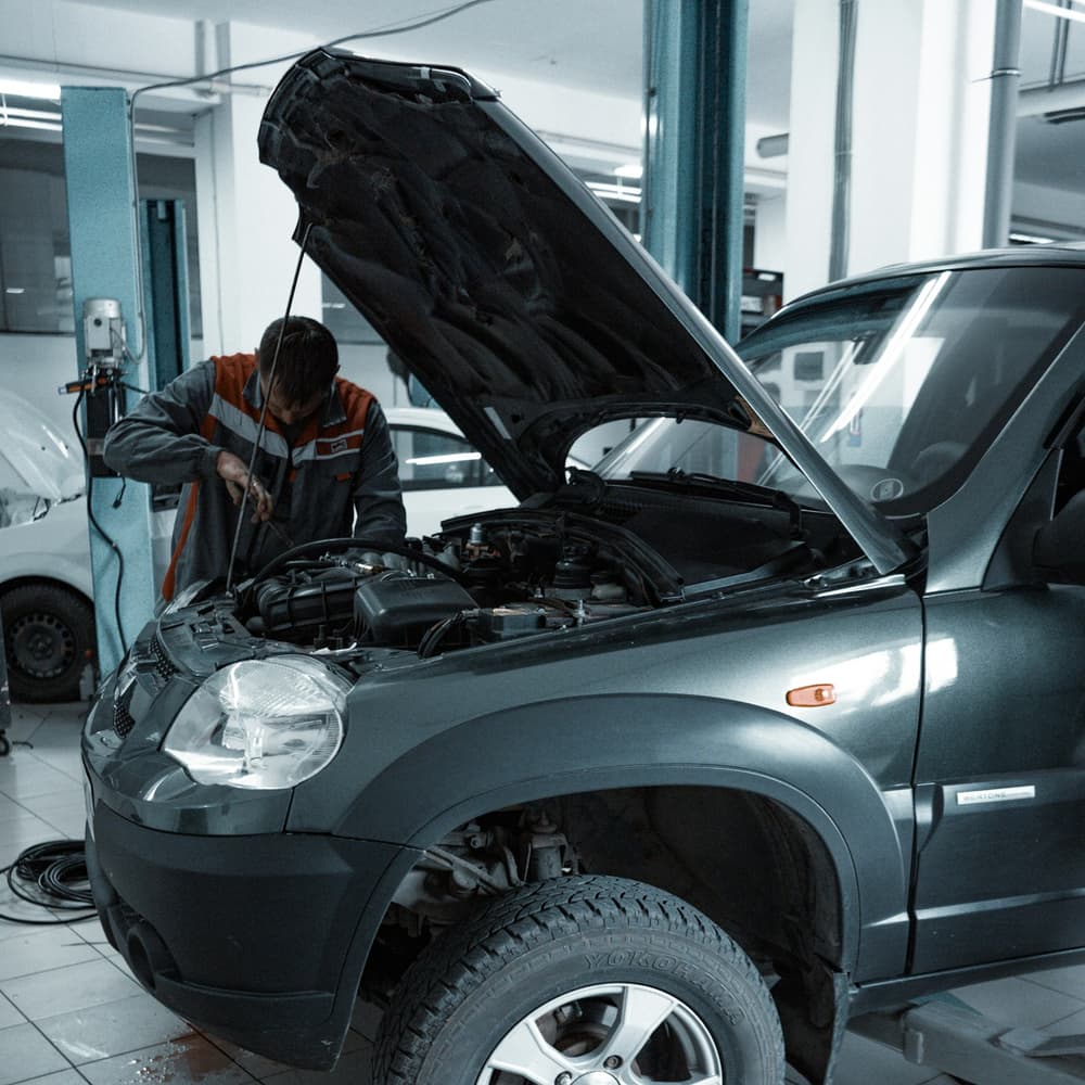 Mechanik przy aucie z otwartą maską w warsztacie