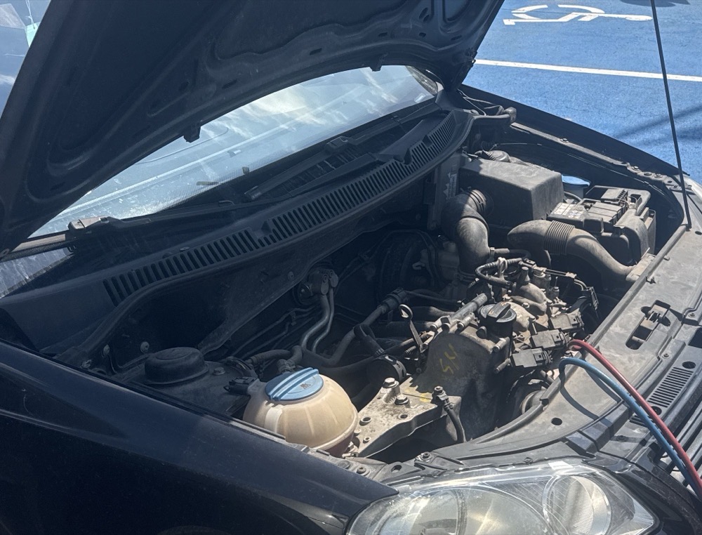 Auto z otwartą maską na nagrzanym parkingu w pełnym słońcu