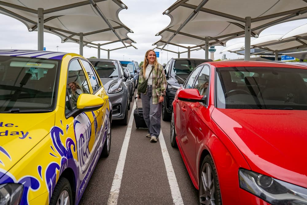 Podróżna z walizką idąca między autami na parkingu po powrocie