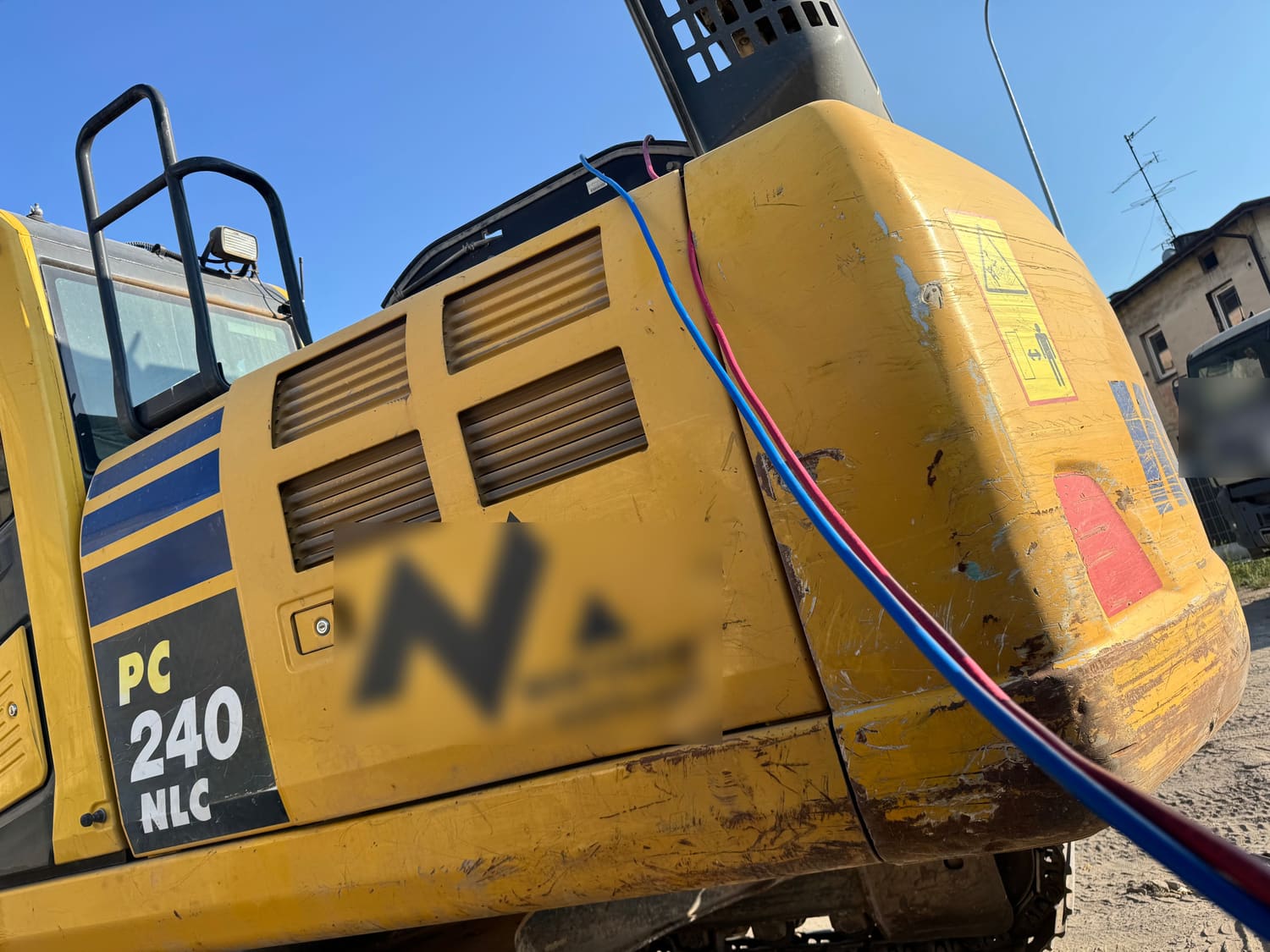 Węże serwisowe podłączone do portów klimatyzacji koparki Komatsu PC240 przy otwartej komorze silnika