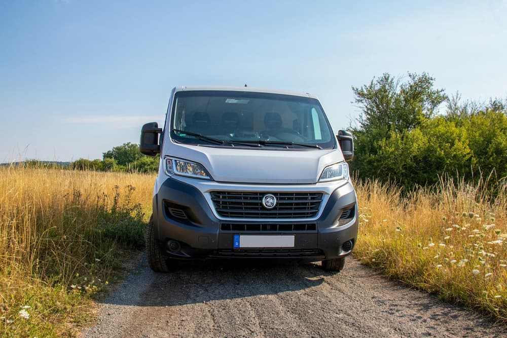 Współczesny Fiat Ducato zaparkowany na polnej drodze wśród traw